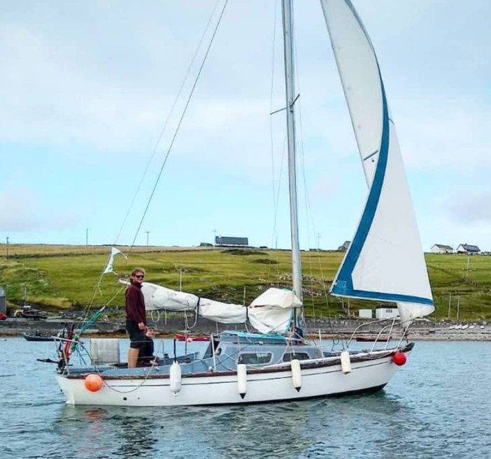a man is standing on a sailboat in the water.
