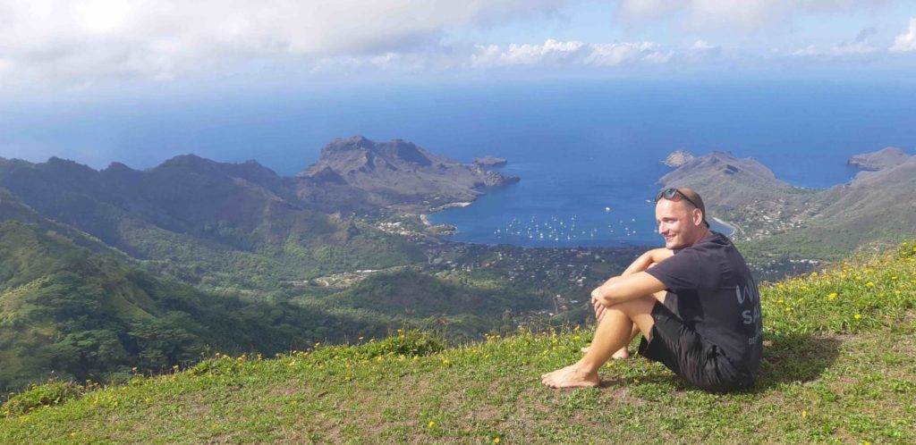 a man sitting on top of a mountain overlooking the ocean.