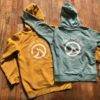 An Ocean Nomads Hoodies - Ladies in yellow and blue placed on a wooden floor.