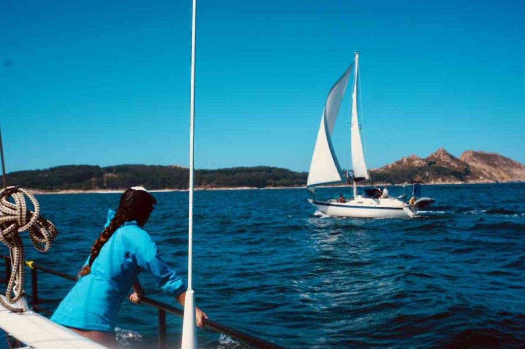 a woman is standing on the bow of a sailboat in the ocean.