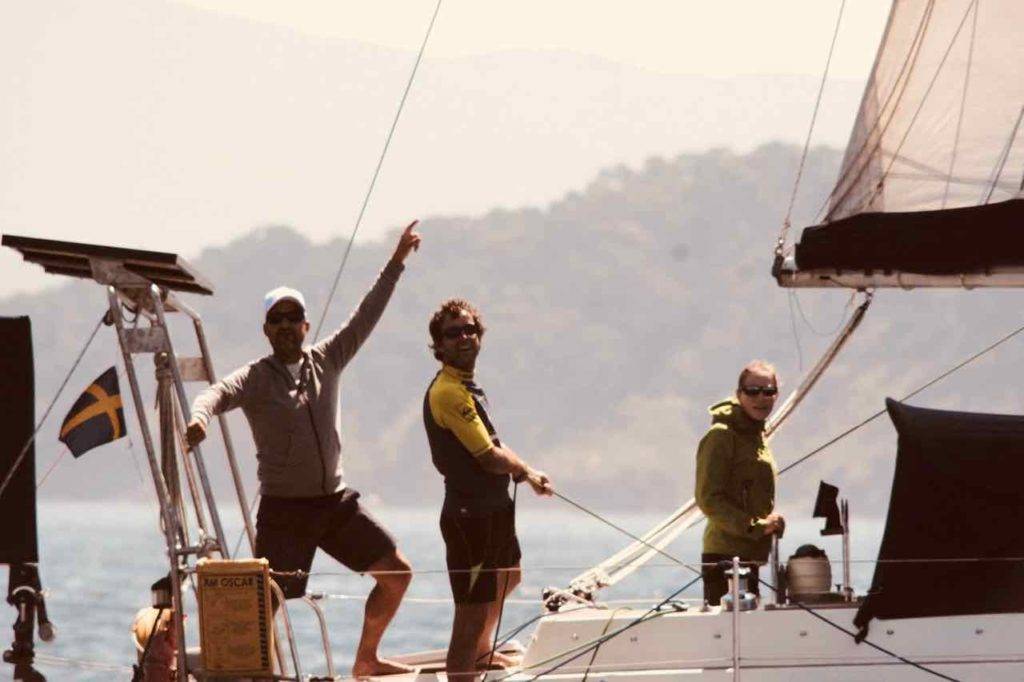 a group of people on a sailboat waving their arms in the air.