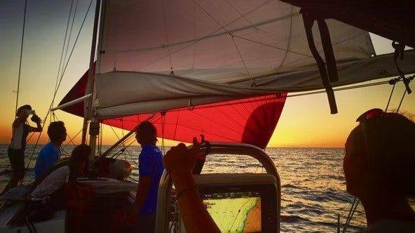a group of people on a sailboat at sunset.