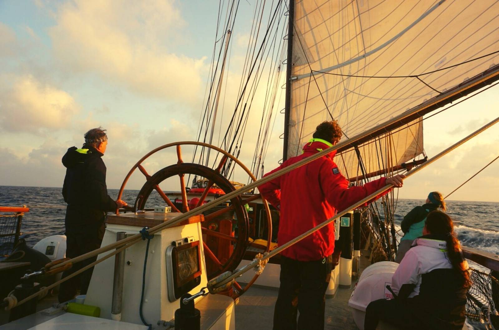 a group of people standing on the deck of a sailboat.