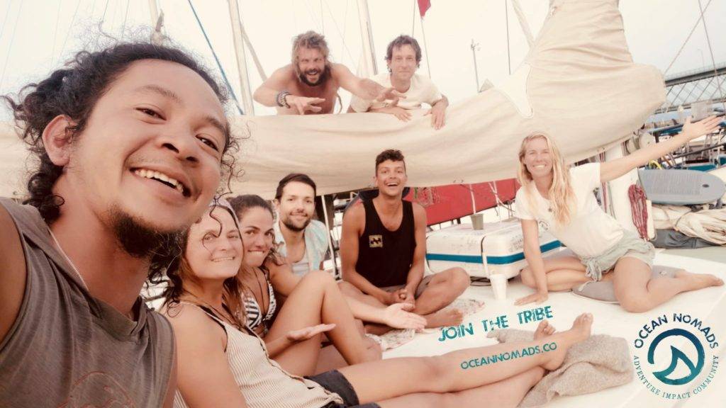a group of people posing for a photo on a sailboat.