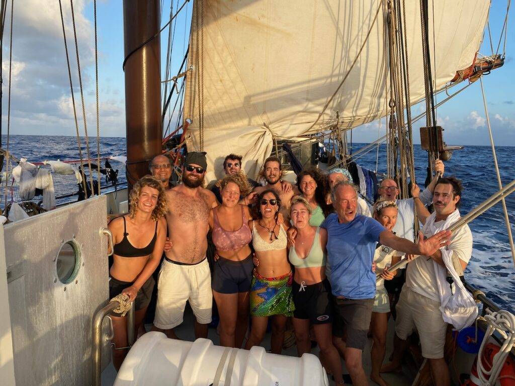 a group of people posing on the deck of a sailboat.