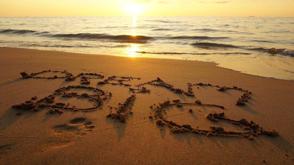 The word dream big written in the sand at sunset.