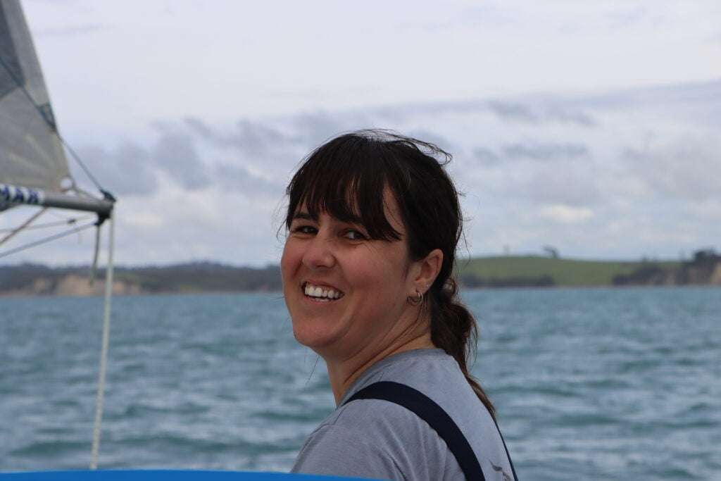 A sailing crew member smiling on a sailboat.