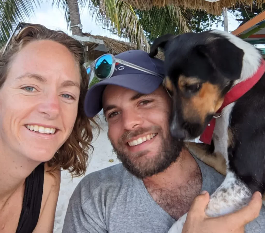 A sailing crew with a dog on a beach.