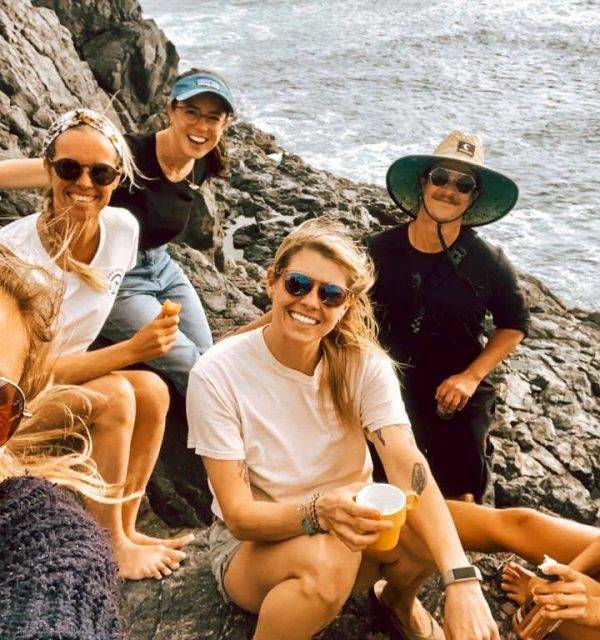 a group of women posing for a selfie on a rocky cliff.