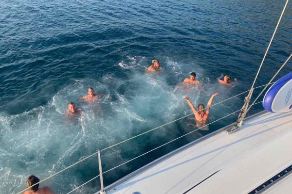 a group of people are swimming in the water on a boat.