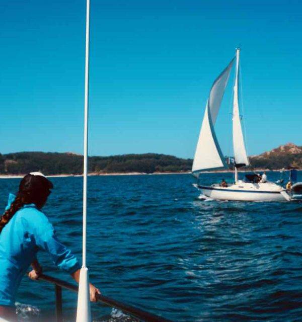 a woman is standing on the bow of a sailboat in the ocean.